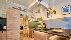 A modern kitchen with wooden cabinets, a central island, pendant lighting, and a view of the outdoors.