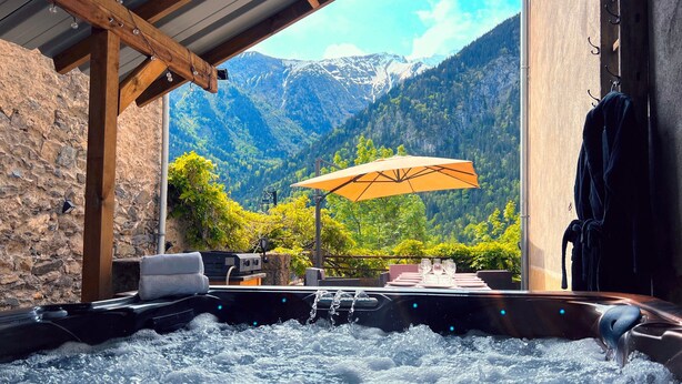 A hot tub with a mountain view, wooden beams, and an umbrella.