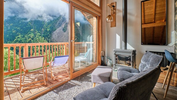 Een gezellige kamer met een grote schuifglazen deur naar een balkon, een open haard en een comfortabele zithoek.