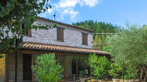 A rustic stone building with a tiled roof, a covered patio with a table, and potted plants. - Stunning home in Sassoferrato (Sassoferrato)