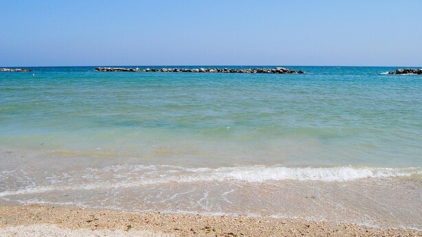 A beach with clear turquoise water, pebbly shore, and a rocky breakwater in the distance. - Stunning home in Sassoferrato (Sassoferrato)