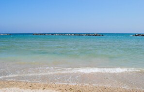 A beach with clear turquoise water, pebbly shore, and a rocky breakwater in the distance. - Stunning home in Sassoferrato (Sassoferrato)
