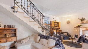 Un salon avec un escalier, un canapé, une table basse et une cheminée.