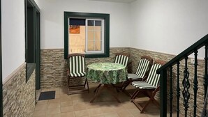A small balcony with a table and four chairs, a window with a view, and a staircase with a railing. - Abades Beach Houses by EstrellaDelNorte (Arico)
