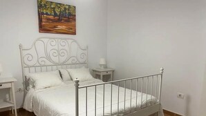 A white metal bed with a headboard, a bedside table, a lamp, and a painting on the wall. - Abades Beach Houses by EstrellaDelNorte (Arico)