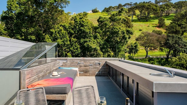 Une terrasse sur le toit comprenant un espace repas, des sièges d’extérieur et une vue sur un paysage verdoyant.