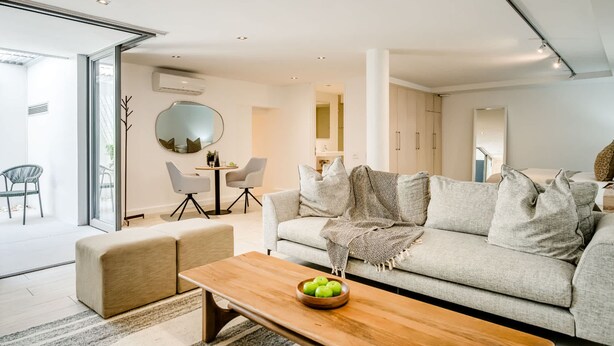 Ein modernes Wohnzimmer mit einer Couch, einem Couchtisch und einem Essbereich mit Stühlen und einem Tisch.