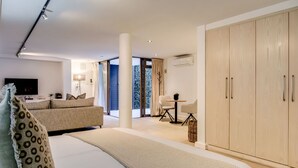 Ein modernes Hotelzimmer mit einem großen Bett, einer Couch, einem Esstisch und einem Kleiderschrank.