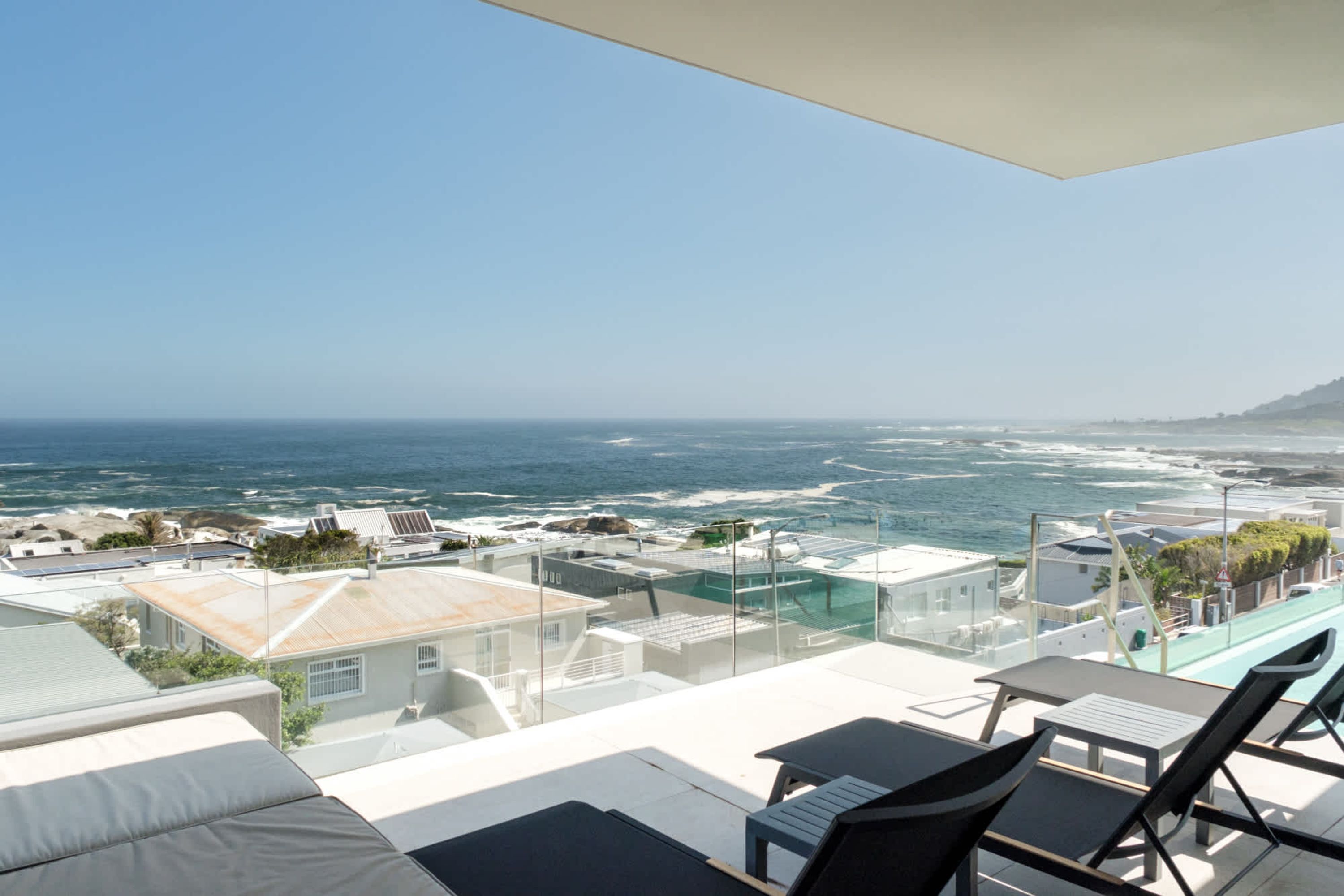 Una terraza en la azotea con vistas al océano, que cuenta con mobiliario de exterior y una piscina.