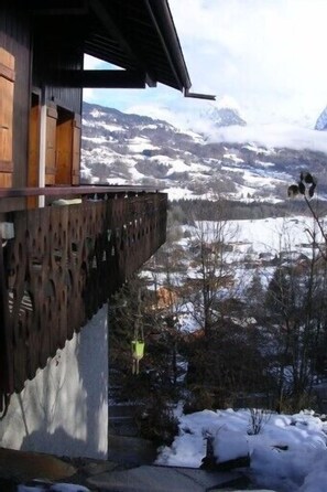 A wooden building with a balcony overlooking a snowy mountainous landscape.