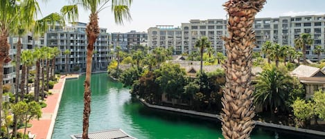 A resort with a canal, palm trees, and modern buildings.