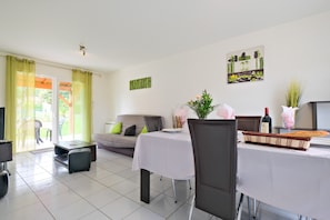 Un coin repas avec une table dressée pour deux personnes, un canapé et un téléviseur.