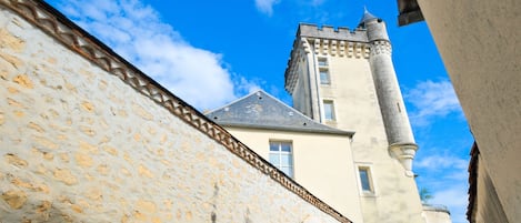 A stone building with a tower, arched windows, and a clear blue sky.