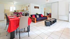 Een moderne woonkamer met een bank, een eethoek en een keuken op de achtergrond.
