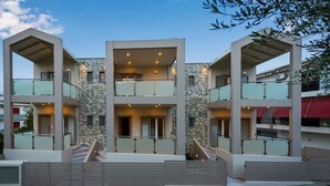 Un edificio residencial moderno de varios pisos, con balcones, fachada de piedra y entrada con portón.
