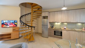 A modern kitchen with wooden cabinets, a built-in refrigerator, a coffee maker, and a glass dining table. - Avia Blue Maisonette - Steps From the Sea (West Mani)