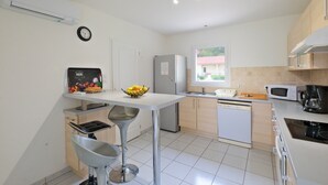 Cozinha moderna com área de jantar, eletrodomésticos de aço inoxidável e janela com vista.