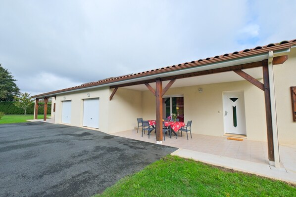 A building with a covered patio area, a table with chairs, and a door.