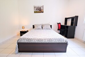 A bedroom with a bed, a nightstand, a desk, and a chair.