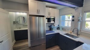 A modern kitchen with stainless steel appliances, dark cabinetry, and a window providing natural light.