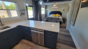 A compact kitchen with a white marble countertop, dark cabinetry, and a dishwasher.
