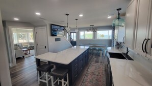 A modern kitchen with a central island, bar stools, and a view of the ocean.