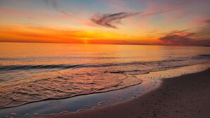 A beach at sunset with waves gently lapping onto the shore.