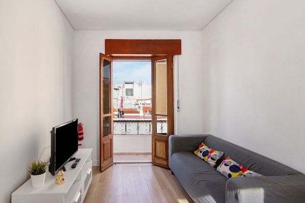 A living room with a TV, sofa, and a balcony door.