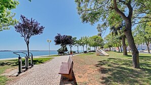 Un chemin pavé agrémenté d’un banc, d’arbres et offrant une vue sur l’eau.
