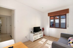 A living room with a white entertainment unit, a grey sofa, and a window with a view of a building.