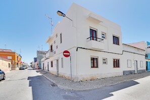 A white building with a no entry sign, a street lamp, and a clear sky.