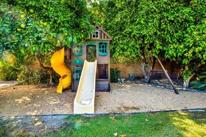 A playground with a slide and a playhouse. - Beautiful and Private 4 Bedroom Private Pool Home (Bermuda Dunes)