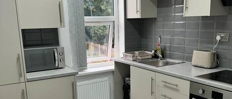 Moderni keittiö, jossa on mikroaaltouuni, pesuallas ja liesi.
