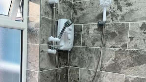A shower with a handheld showerhead and a wall-mounted control panel, set against a tiled wall. - City Chic Retreat In Birmingham (Birmingham)