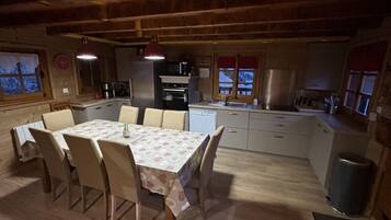 A kitchen with a dining table, chairs, and various appliances.
