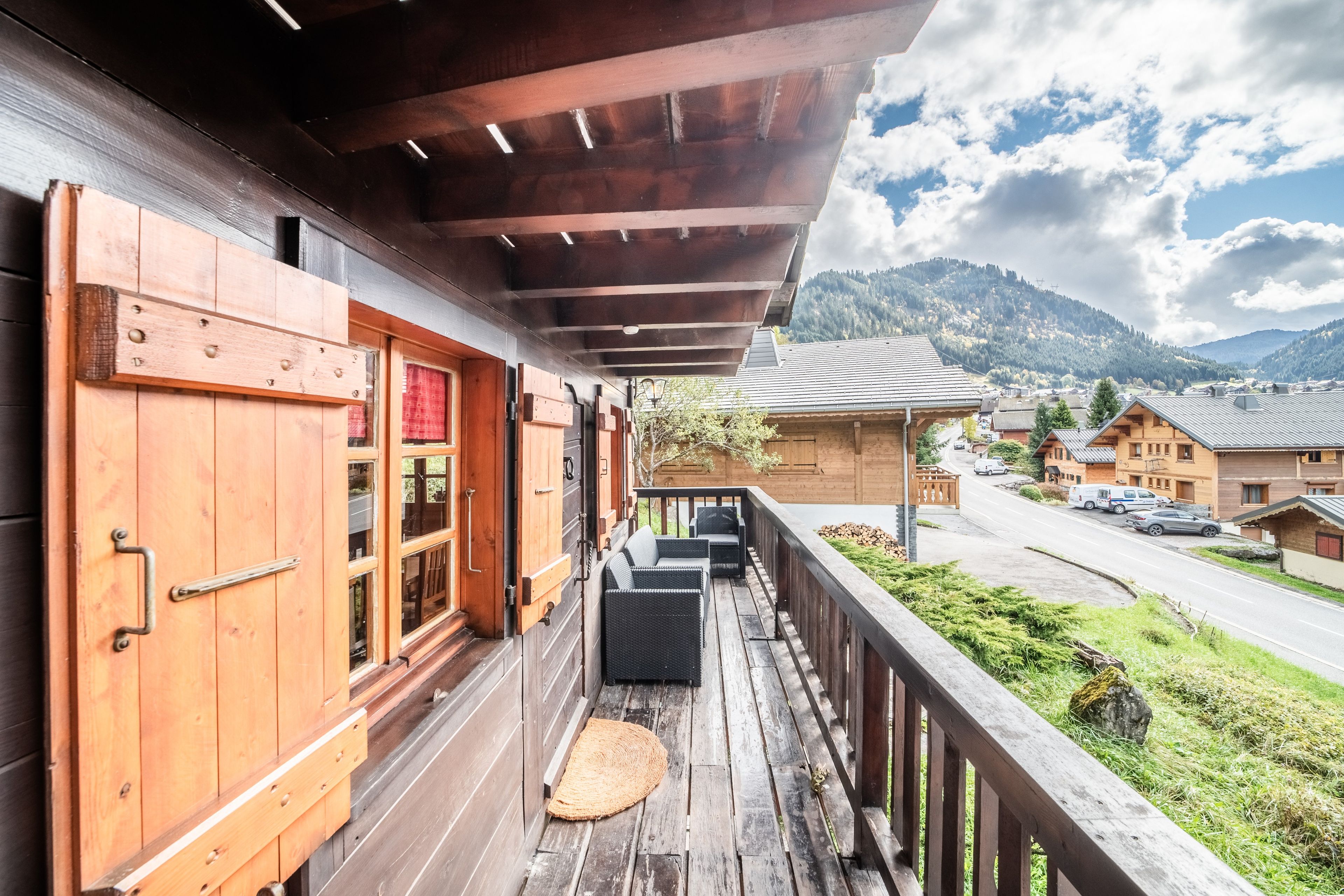 Un balcon en bois offrant une vue sur une montagne et une route.