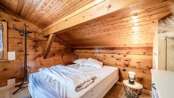 Une chambre à coucher chaleureuse, avec des murs en bois, comprenant un lit, une table de chevet, une chaise et une lampe sur pied.