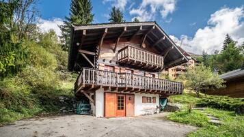 A traditional chalet with a wooden balcony and a stone entrance.