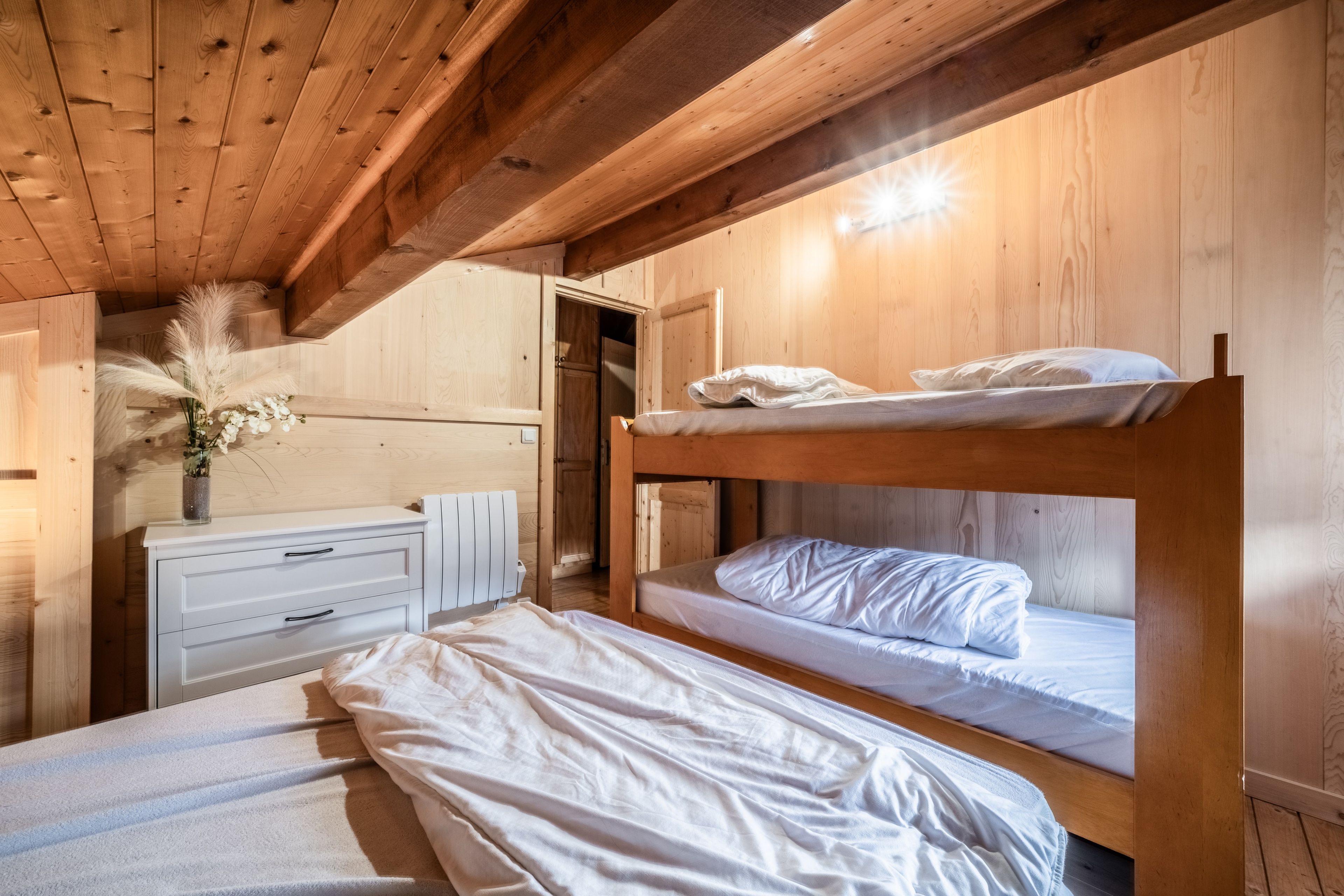 A wooden bunk bed room with a dresser and a radiator.