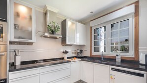 Eine moderne Küche mit weißen Schränken, einer schwarzen Arbeitsplatte, einem eingebauten Backofen und einem Fenster mit Blick.
