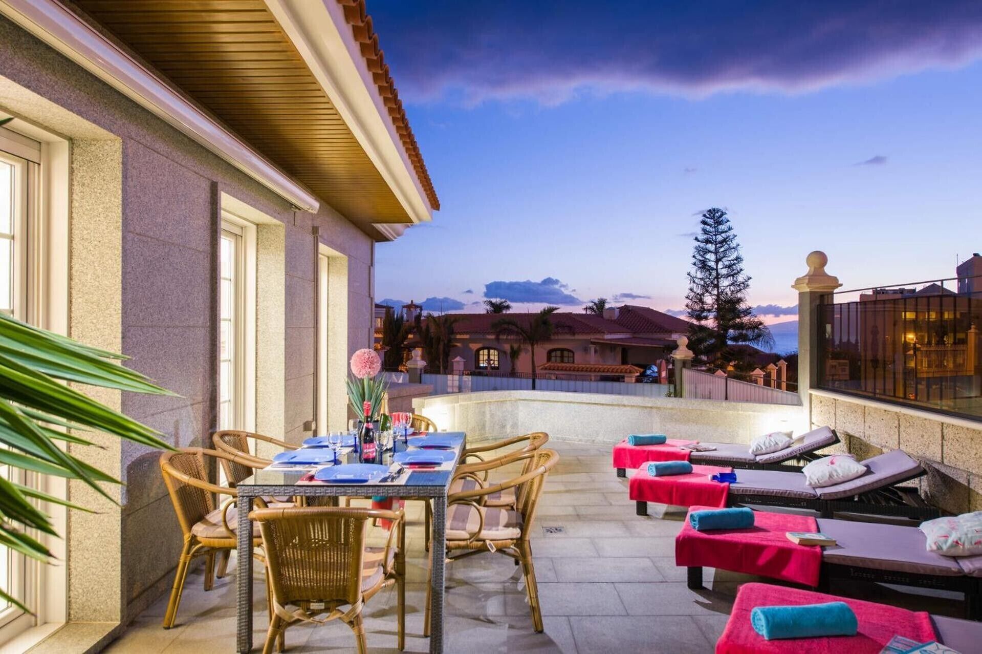 An outdoor patio with wicker furniture, a dining table set, and a pool area with lounge chairs.