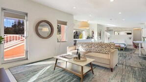 A modern living room with a sofa, coffee table, and a dining area with a table and chairs. - The Gower Street Bungalows by AvantStay (Los Angeles)