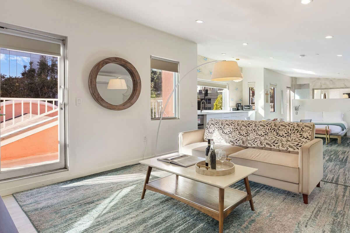 A modern living room with a sofa, coffee table, and a dining area with a table and chairs.