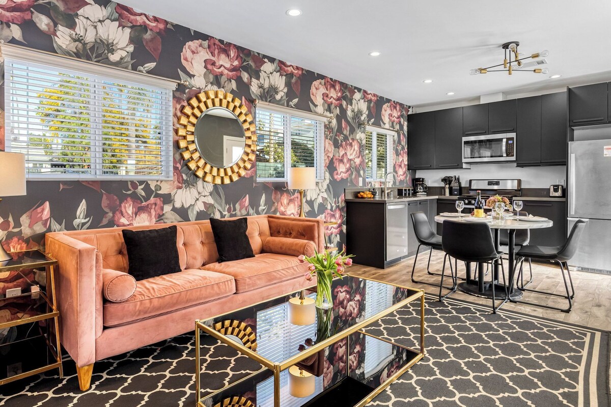 A modern kitchen with dark cabinets, a stainless steel refrigerator, and a dining area with a round table and chairs.