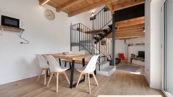 Une cuisine moderne avec une table et des chaises en bois, un four à micro-ondes encastré et un escalier menant à un niveau supérieur.