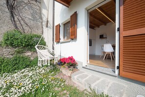 Une maison avec un jardin, une chaise blanche et une porte en bois.
