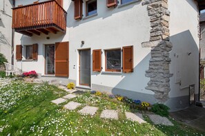 Un bâtiment blanc avec des volets en bois, une colonne en pierre et un balcon.