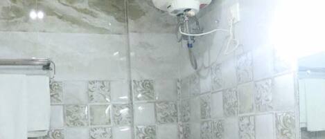 Ein Badezimmer mit Toilette, Waschbecken, Dusche und einem an der Wand montierten Warmwasserbereiter.