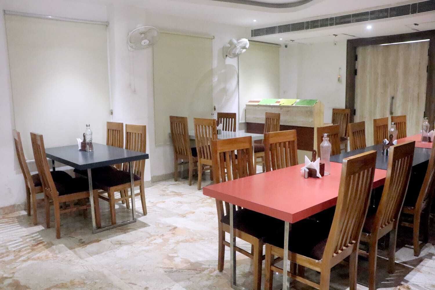 Een vergaderruimte met meerdere tafels en stoelen, een whiteboard en een grote spiegel.