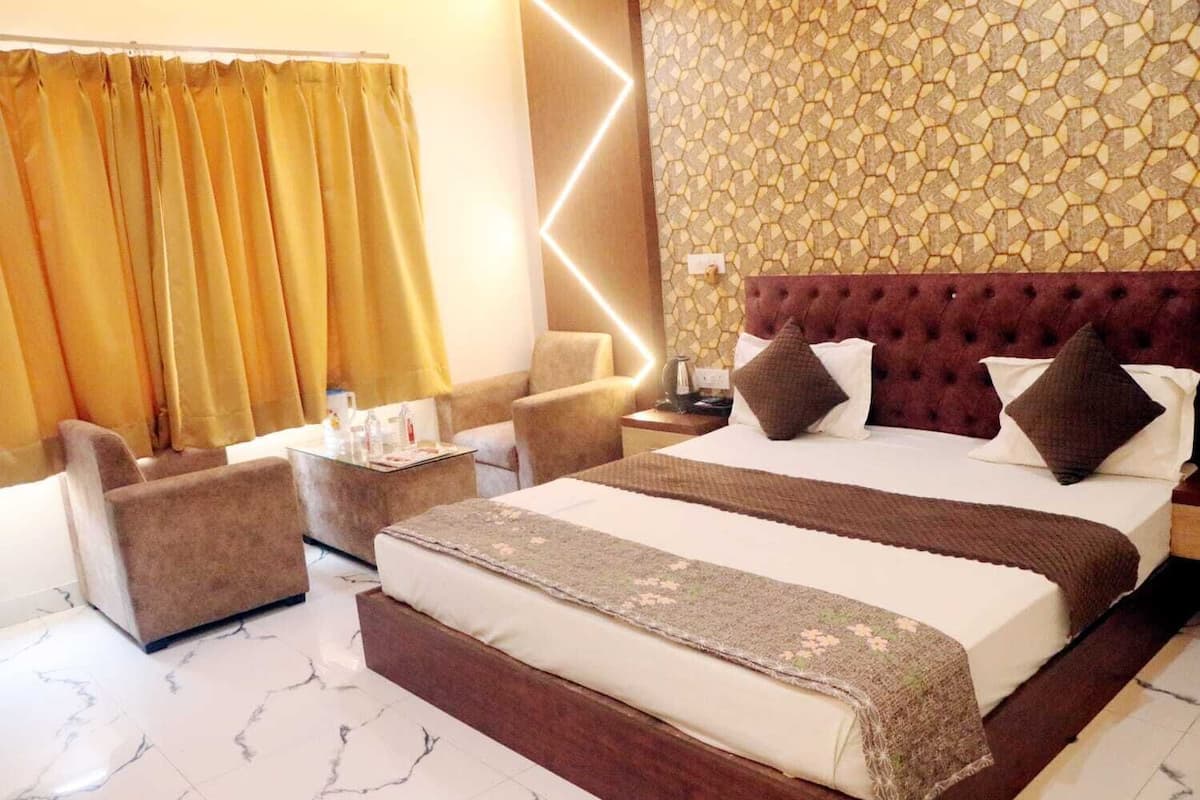 A hotel room with a large bed, a sofa, a small table, and a nightstand.